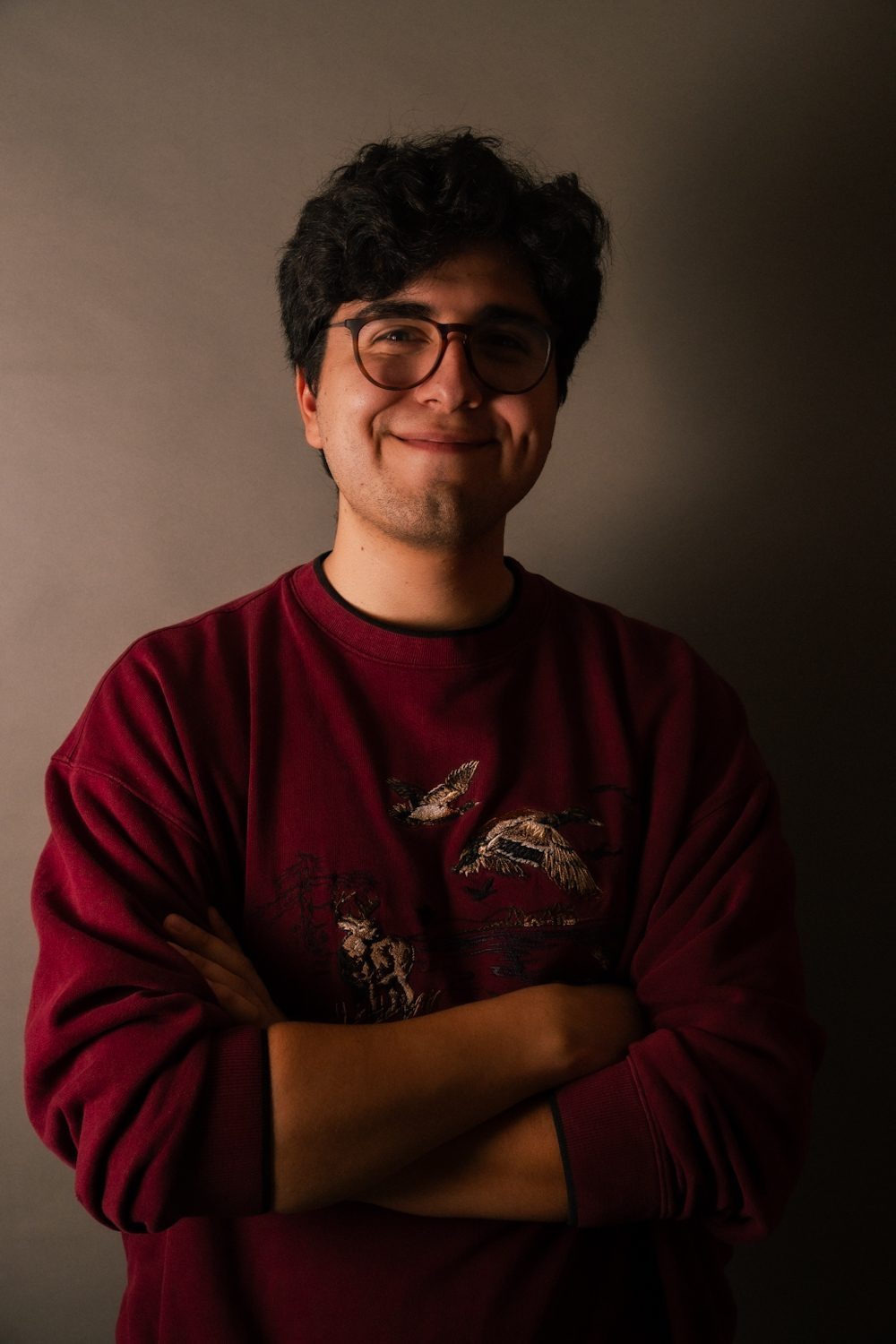 Studio portrait, subject with arms folded and a broad smile.