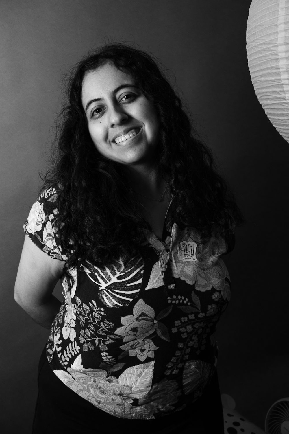 Black and white portrait, subject in a floral shirt beside a paper lantern.