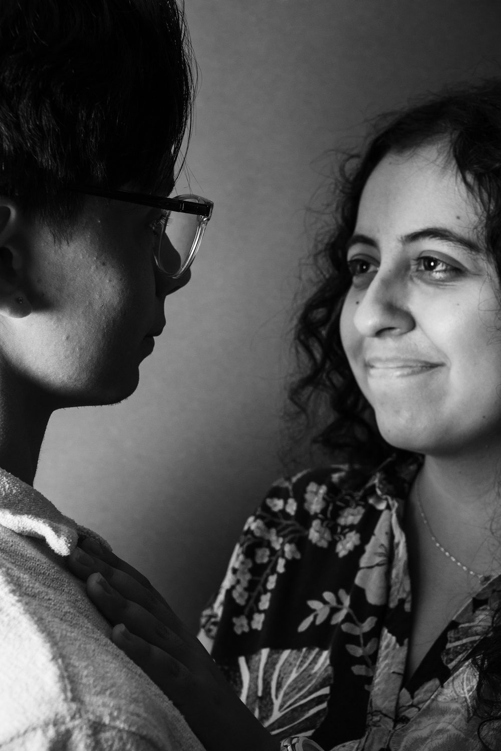 Black and white portrait of two people standing close, one looking to camera.