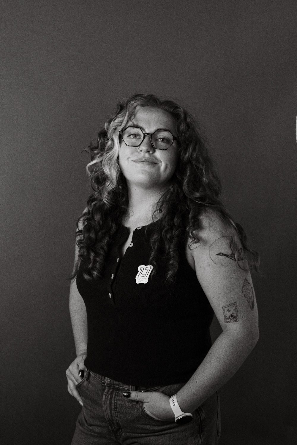 Studio portrait, subject standing with one hand in a pocket, tattooed arm showing.