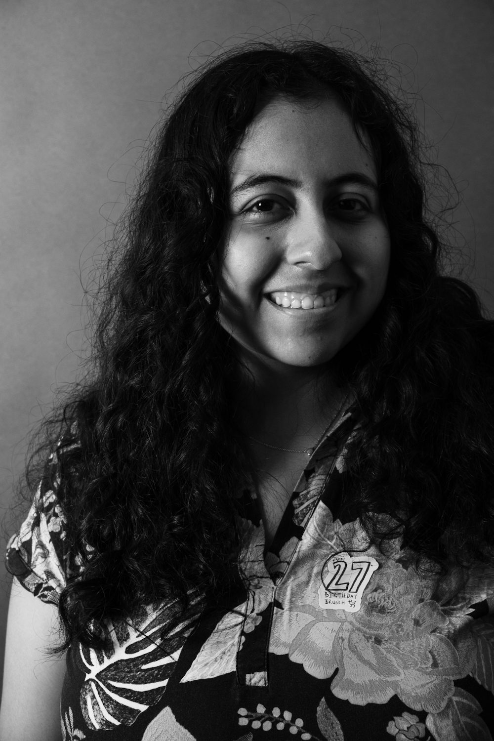 Black and white portrait, subject laughing, long dark curly hair.