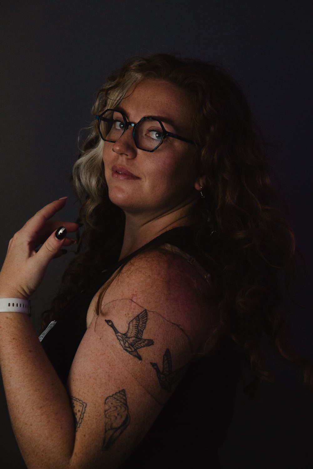 Low-key portrait, subject looking back over a tattooed shoulder.