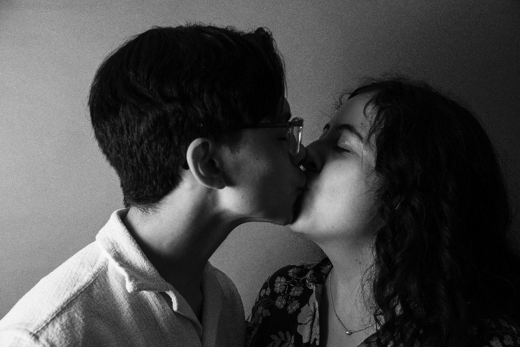 Black and white portrait of two people kissing.