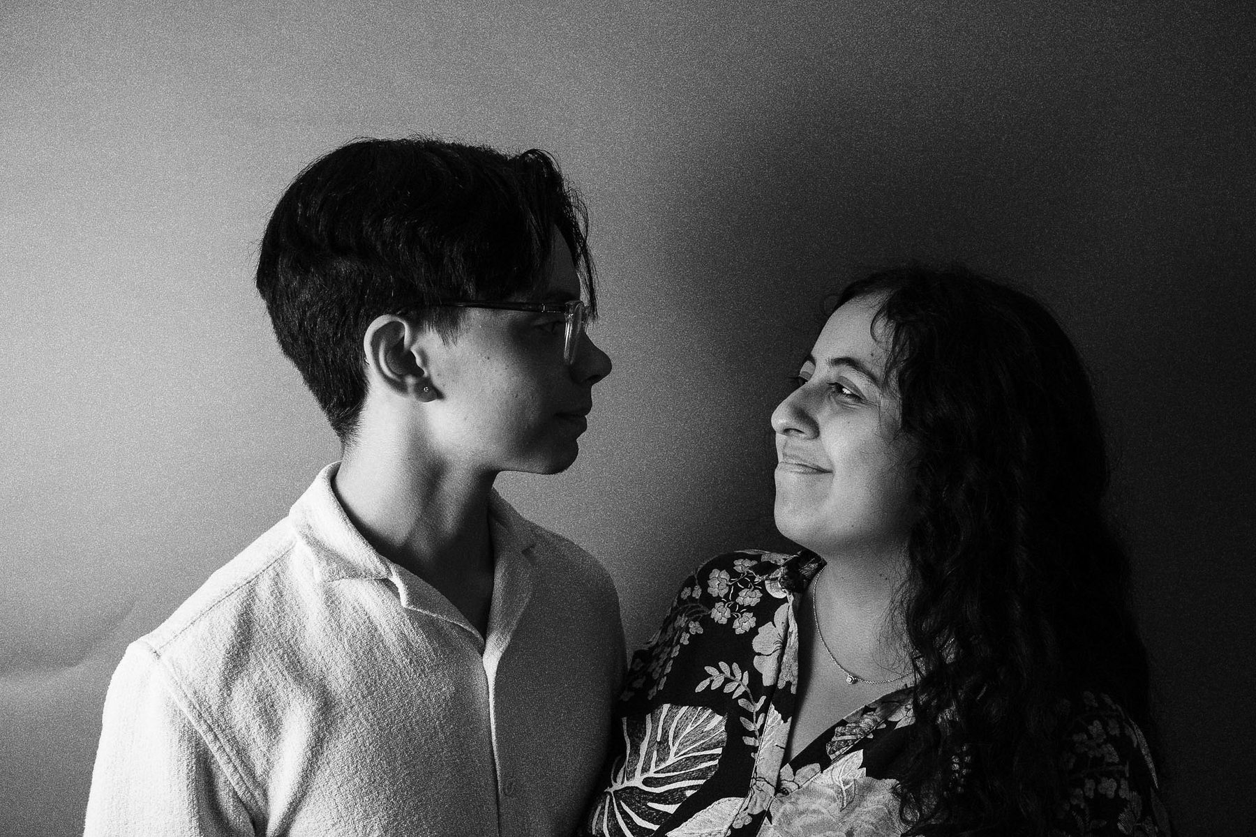Black and white portrait of two people turned toward each other, both smiling.